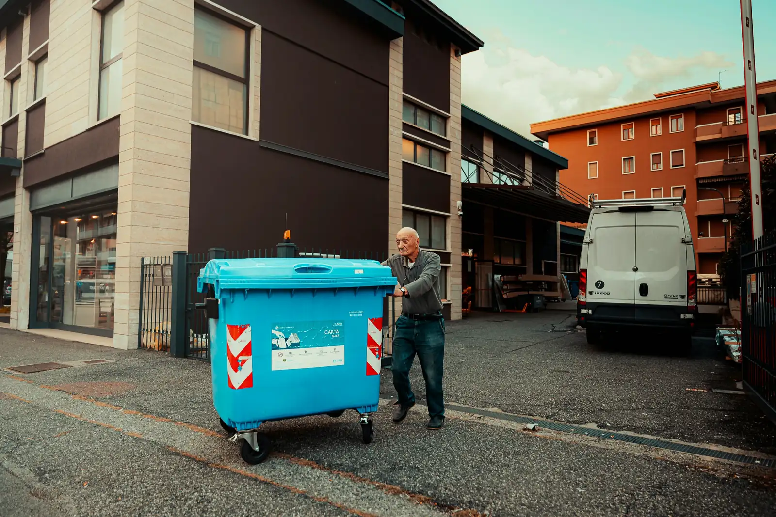 A blue paper recycling container being wheeled out