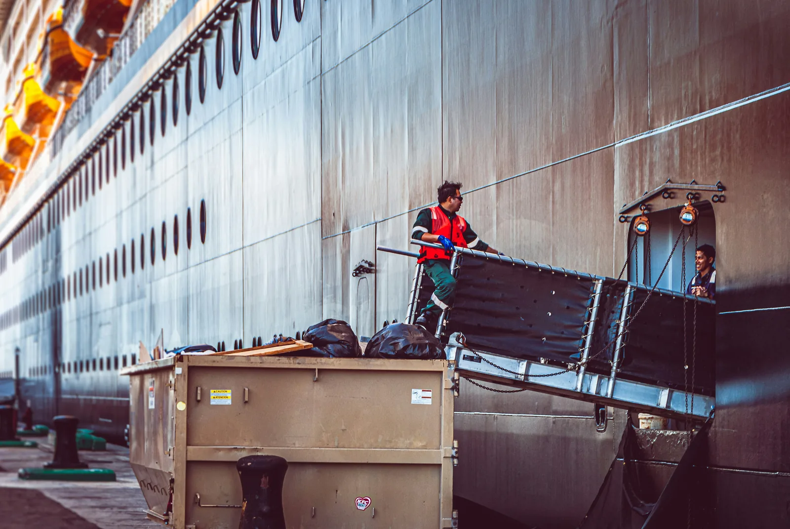 A roll-off container on a dock beside a ship gangway