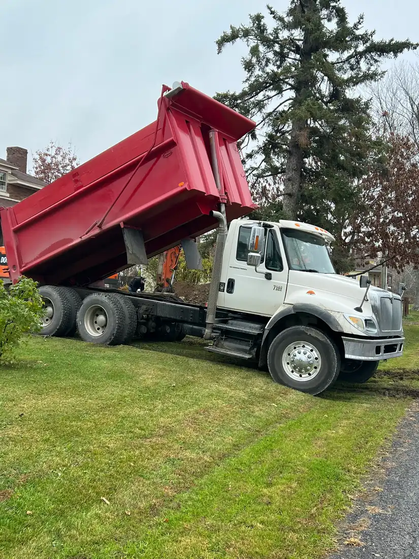 A dump truck with its body raised beside a driveway