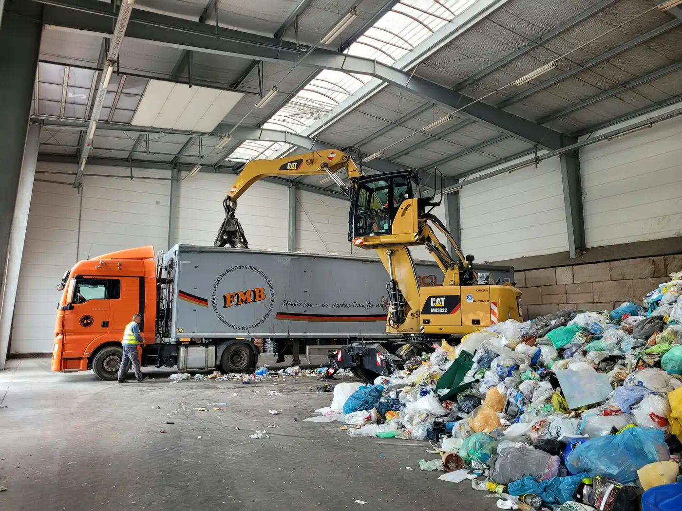A grapple loading a trailer inside a transfer station