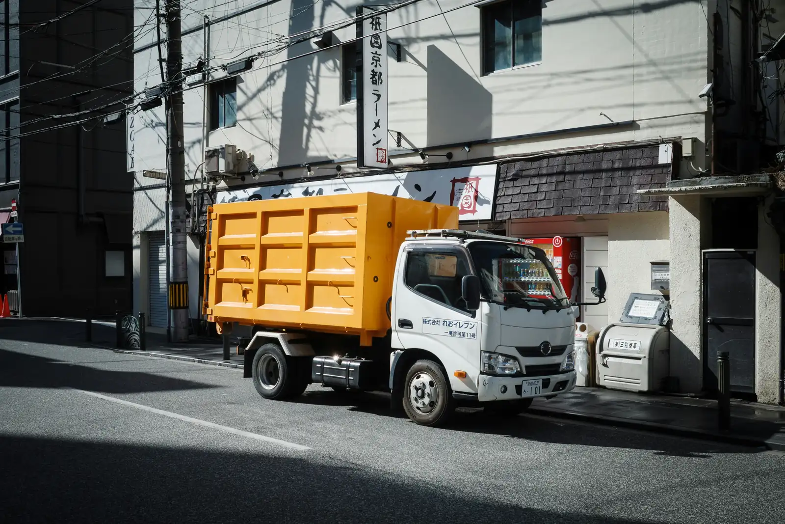 An orange hook-lift container truck parked on a street