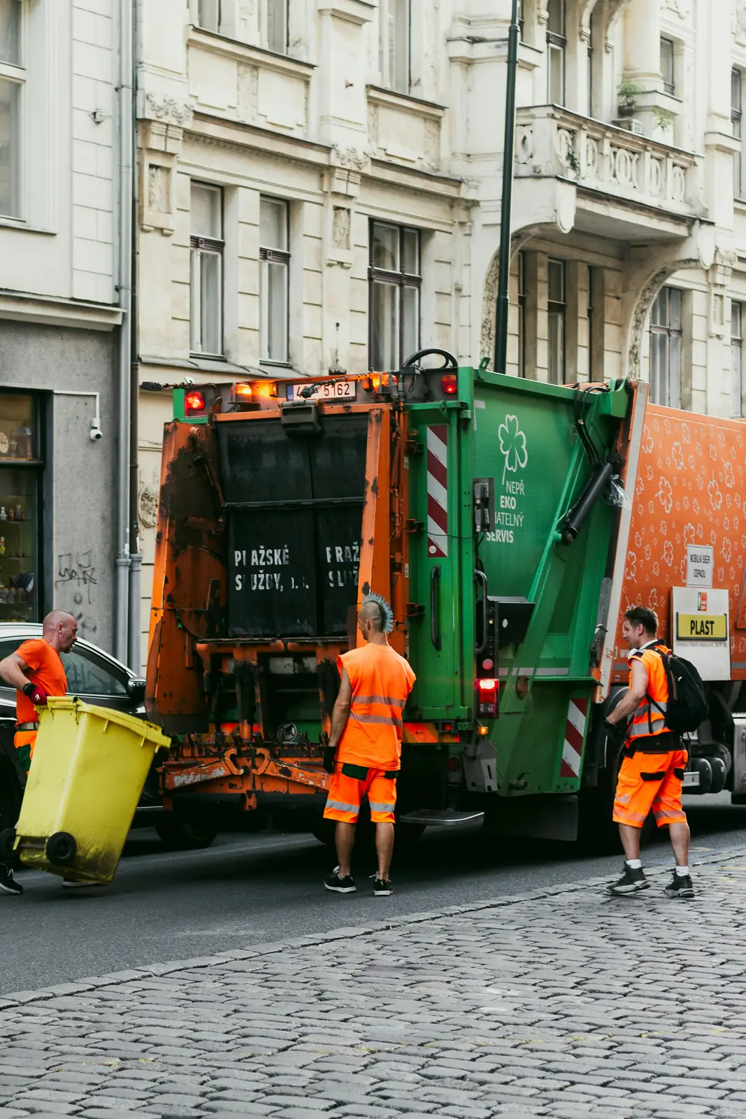 A three-man crew emptying wheelie bins into a truck