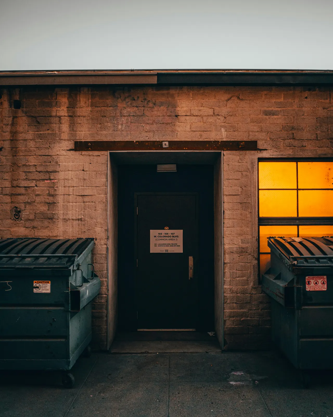 Two front-load dumpsters flanking a brick doorway